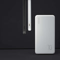 White ultra-thin power bank beside a black one on a dark background