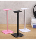 Pink, black and white aluminum headphone stands on a desk