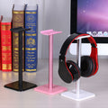 Black, pink and white headphone stands beside a monitor